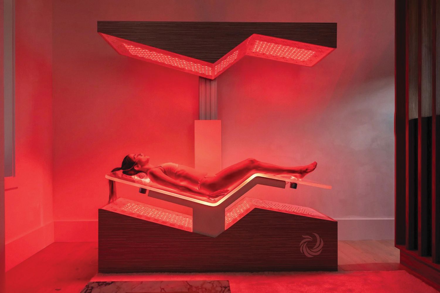 A person relaxes on a red light therapy bed in a serene spa setting, promoting wellness and rejuvenation.