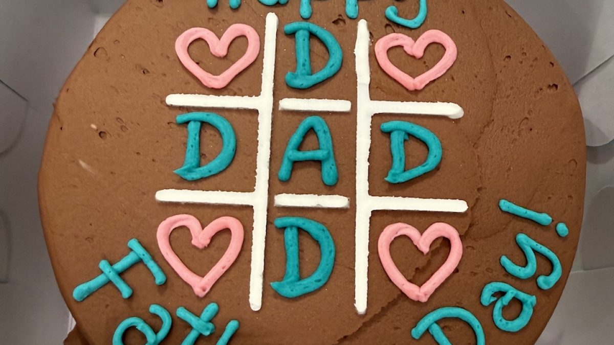 Chocolate cake decorated with colorful icing reading "Happy Father's Day!" and heart designs.