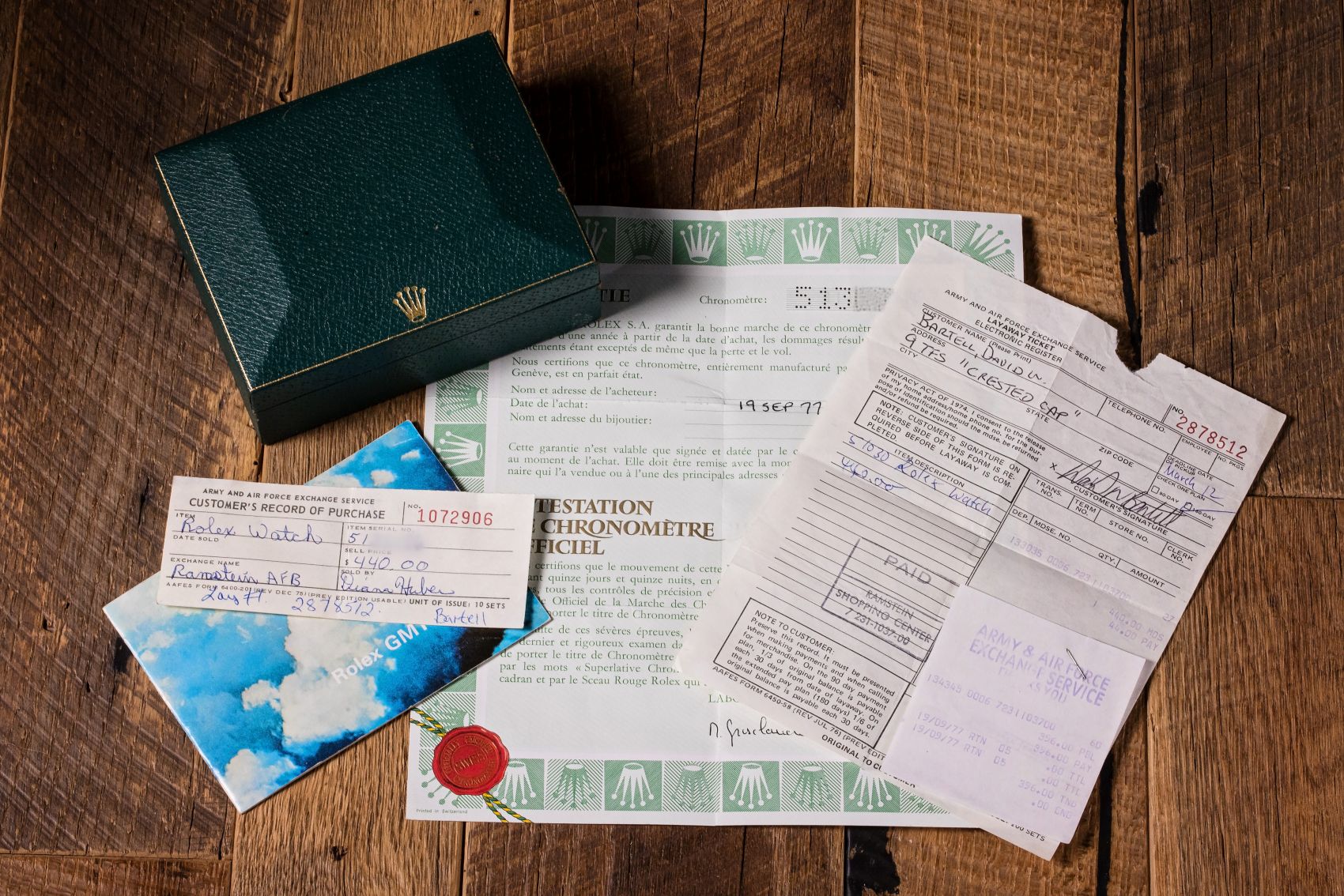 Green Rolex box with papers, including purchase records and authenticity certificates for a GMT-Master watch.