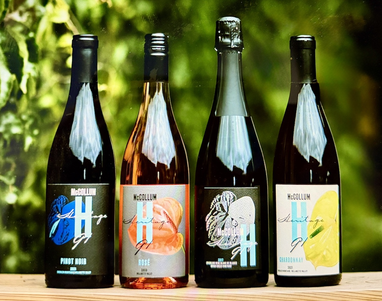 Four bottles of McCollum wines showcasing Pinot Noir, Rosé, and Chardonnay against a blurred green background.