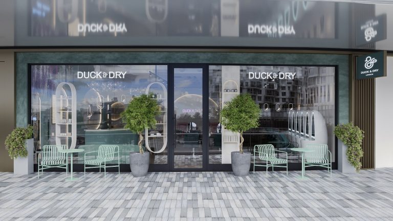 Stylish exterior of Duck & Dry at Battersea Power Station, featuring seating, greenery, and modern architectural design.