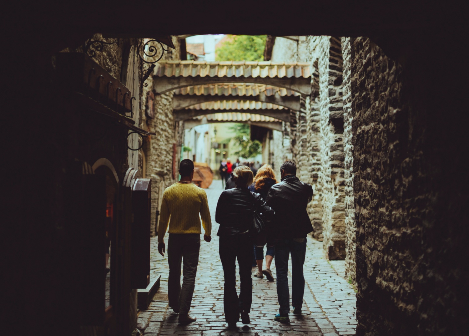 Visitors stroll through a narrow, cobblestone street in Tallinn's Old Town, surrounded by medieval buildings.