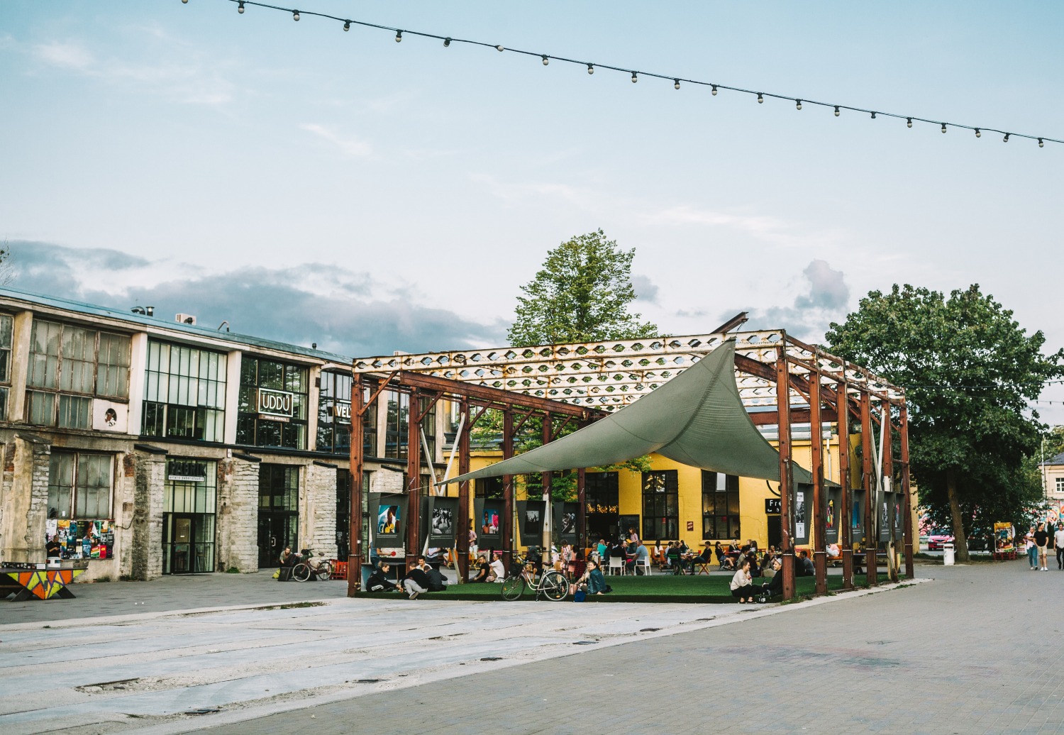 A vibrant outdoor gallery and chill area with people relaxing, surrounded by creative buildings in Telliskivi Creative City.
