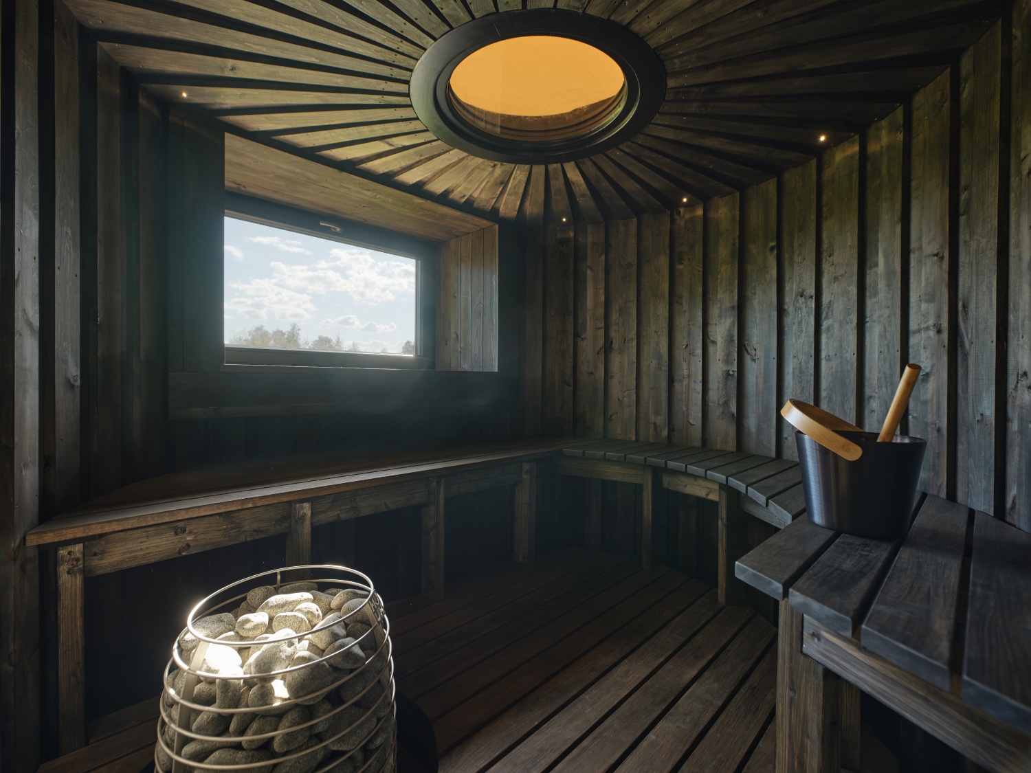 Modern sauna interior featuring wooden benches, a rock heater, and a window allowing natural light.