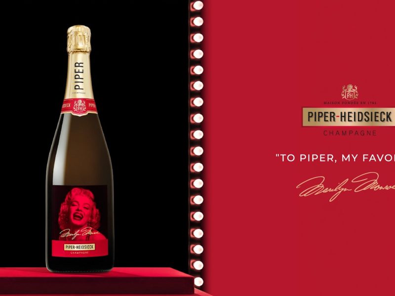 Piper-Heidsieck champagne bottle featuring a Marilyn Monroe design with the text "To Piper, my favorite" on a red backdrop.