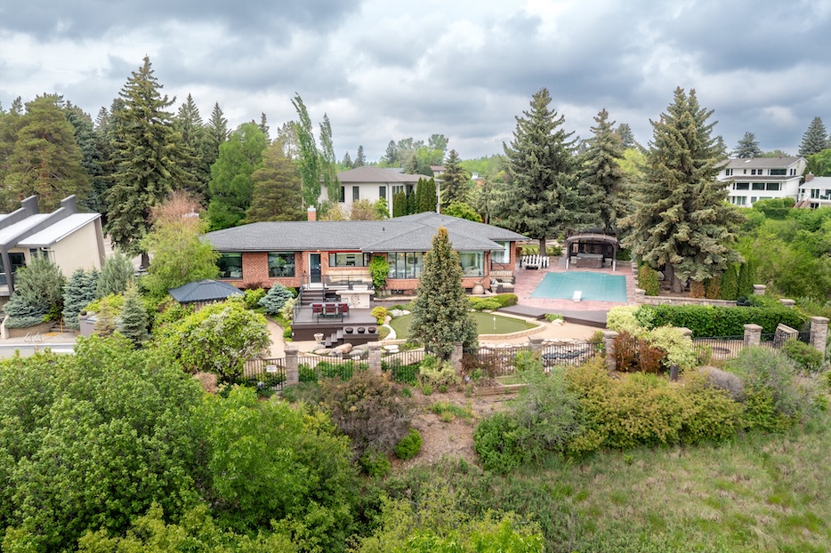 Drone view of a beautifully landscaped property in Saskatoon featuring a pool, gardens, and modern architecture.