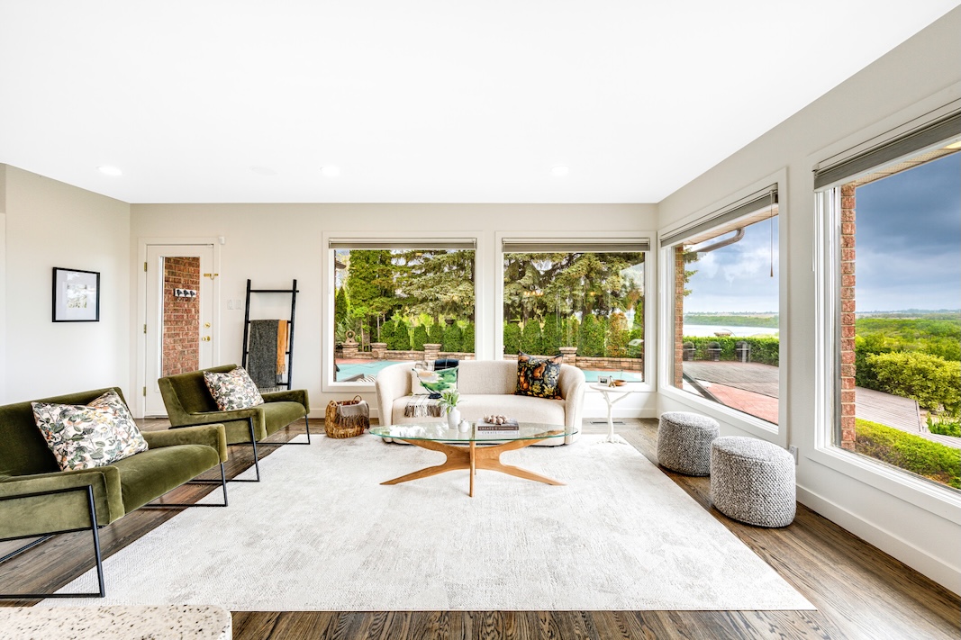 Bright living space with modern furniture and large windows showcasing lush outdoor scenery above Saskatoon's landscape.