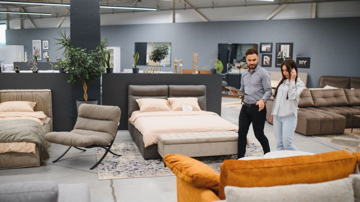 A man and a woman explore a furniture store, discussing personalized shopping experiences with various displays in the background.