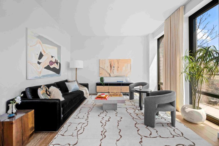 Modern living room showcasing a black sofa, abstract artwork, and large windows with natural light, creating a stylish atmosphere.