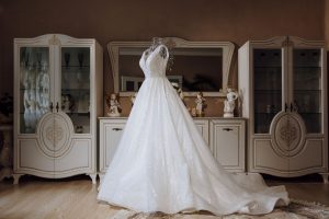 Luxury wedding dress featuring intricate detailing and a flowing train, displayed against an elegant background.