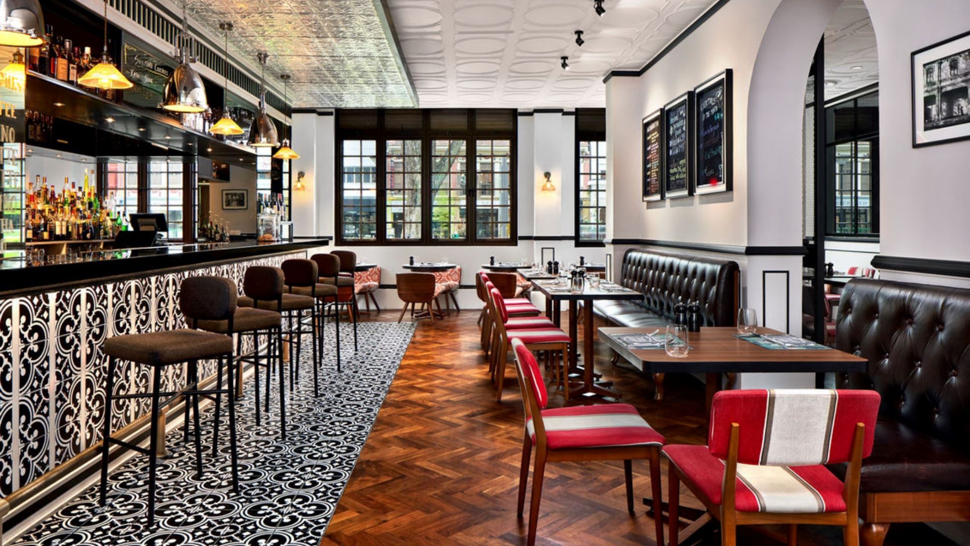 Stylish restaurant interior with a bar, wooden floors, and various seating arrangements, creating a contemporary atmosphere.