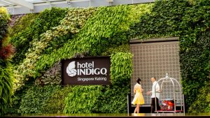 Contemporary hotel entrance featuring lush greenery and the Hotel Indigo sign in Singapore Katong.