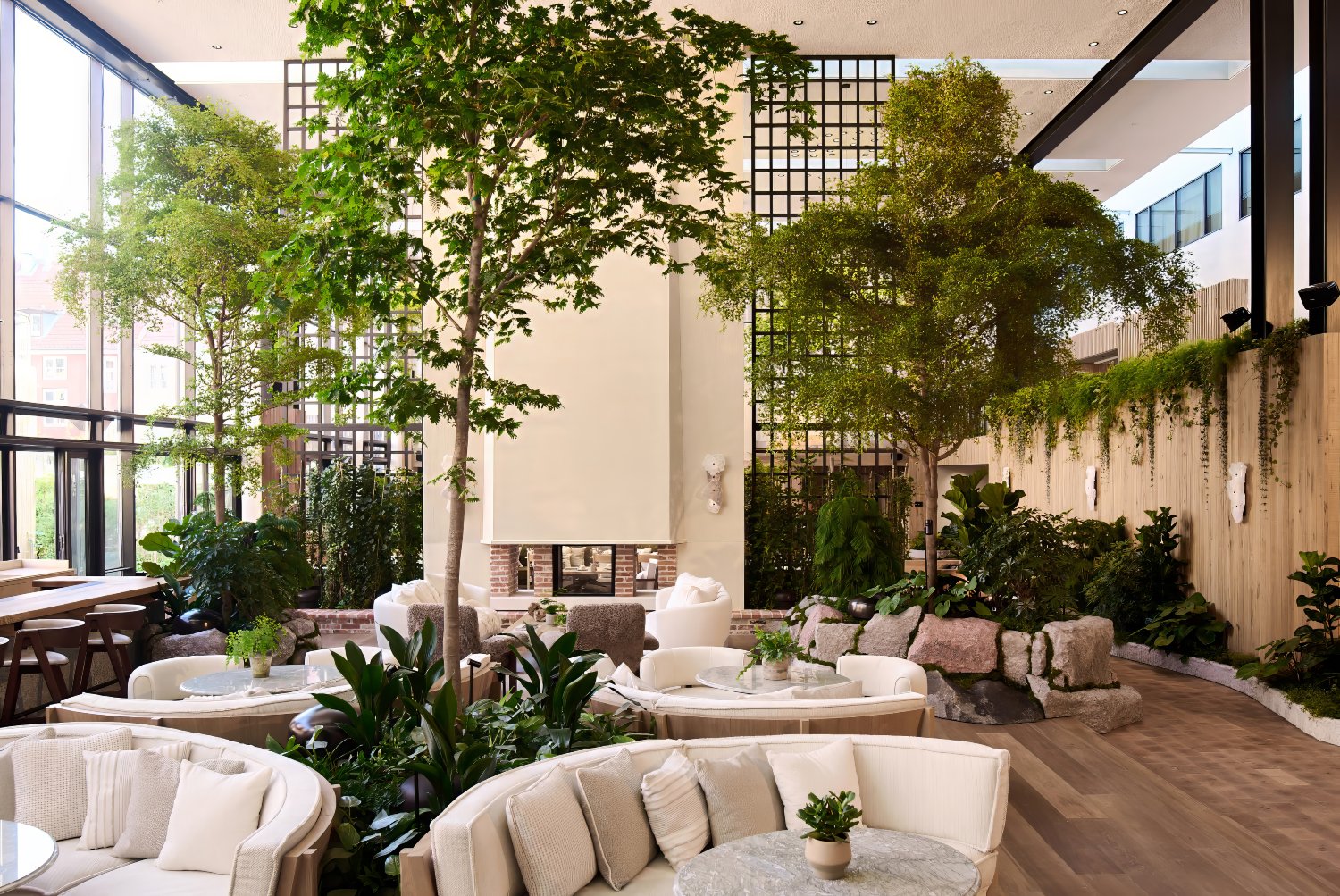 Lush indoor garden with contemporary seating and large windows, creating a serene eco-luxury atmosphere in Copenhagen.
