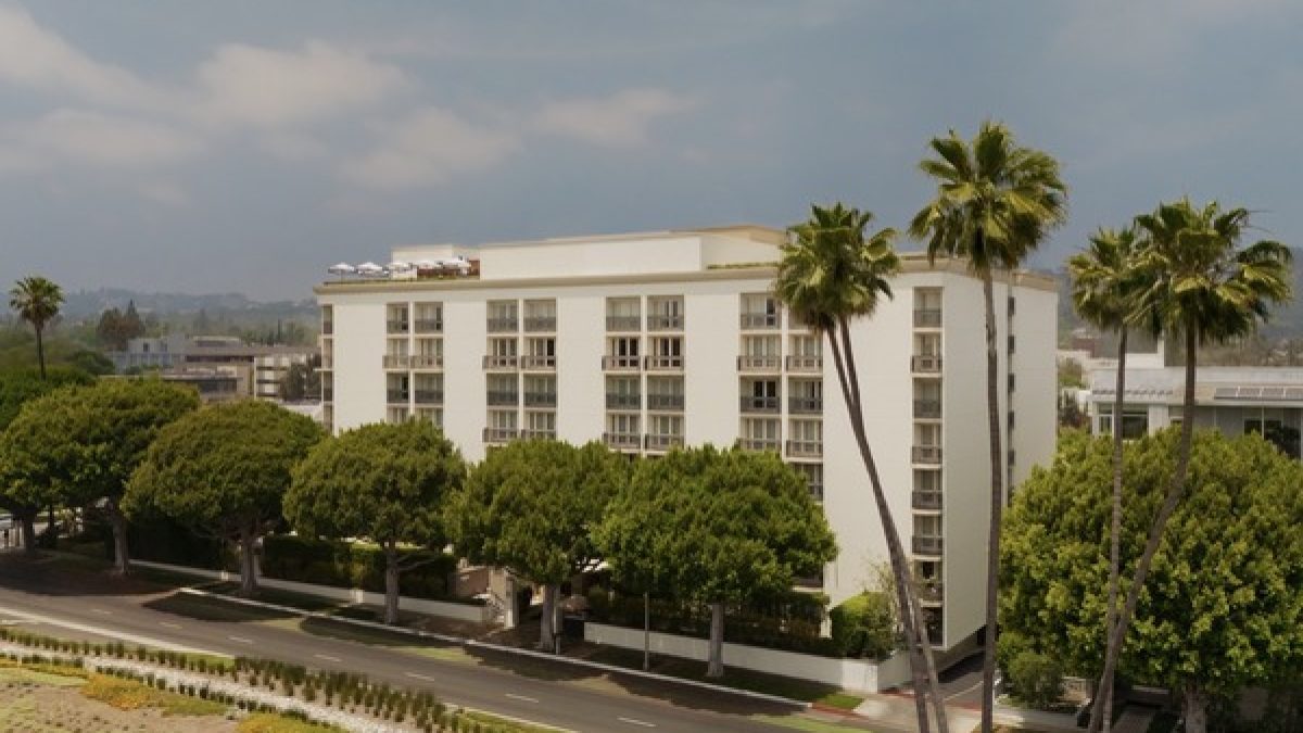 Beverly Hills hotel surrounded by lush trees, showcasing modern architecture against a clear sky.