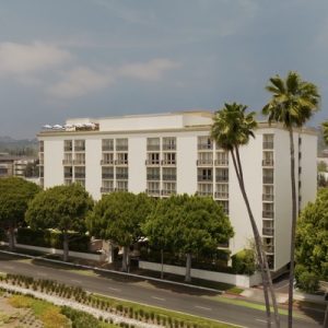 Beverly Hills hotel surrounded by lush trees, showcasing modern architecture against a clear sky.