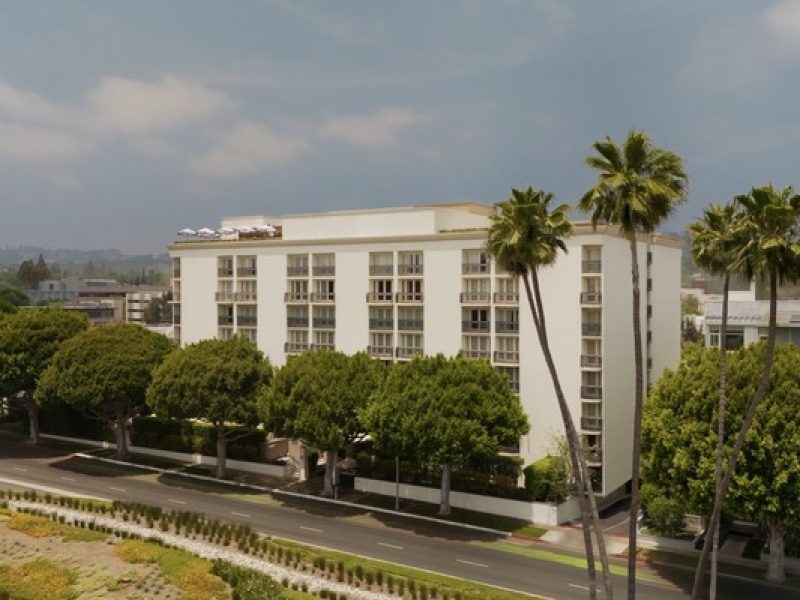 Beverly Hills hotel surrounded by lush trees, showcasing modern architecture against a clear sky.