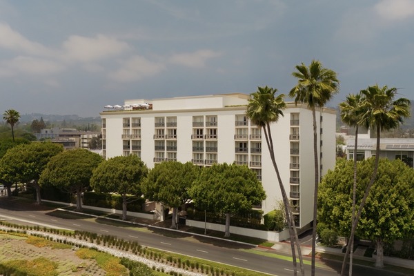 Beverly Hills hotel surrounded by lush trees, showcasing modern architecture against a clear sky.