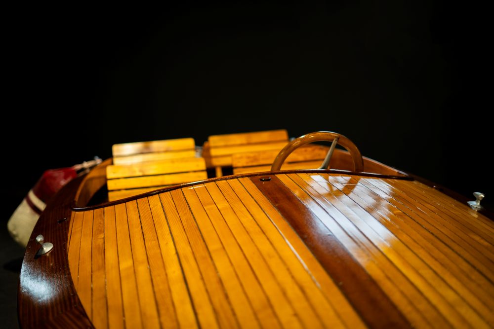 Classic wooden boat interior showcasing polished wood grain and seating, reflecting luxury and craftsmanship.