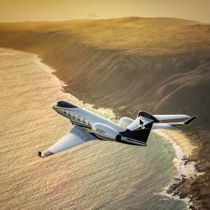 Flexjet's Gulfstream G500 jet flying over a coastal landscape during sunset, showcasing luxury and advanced design.