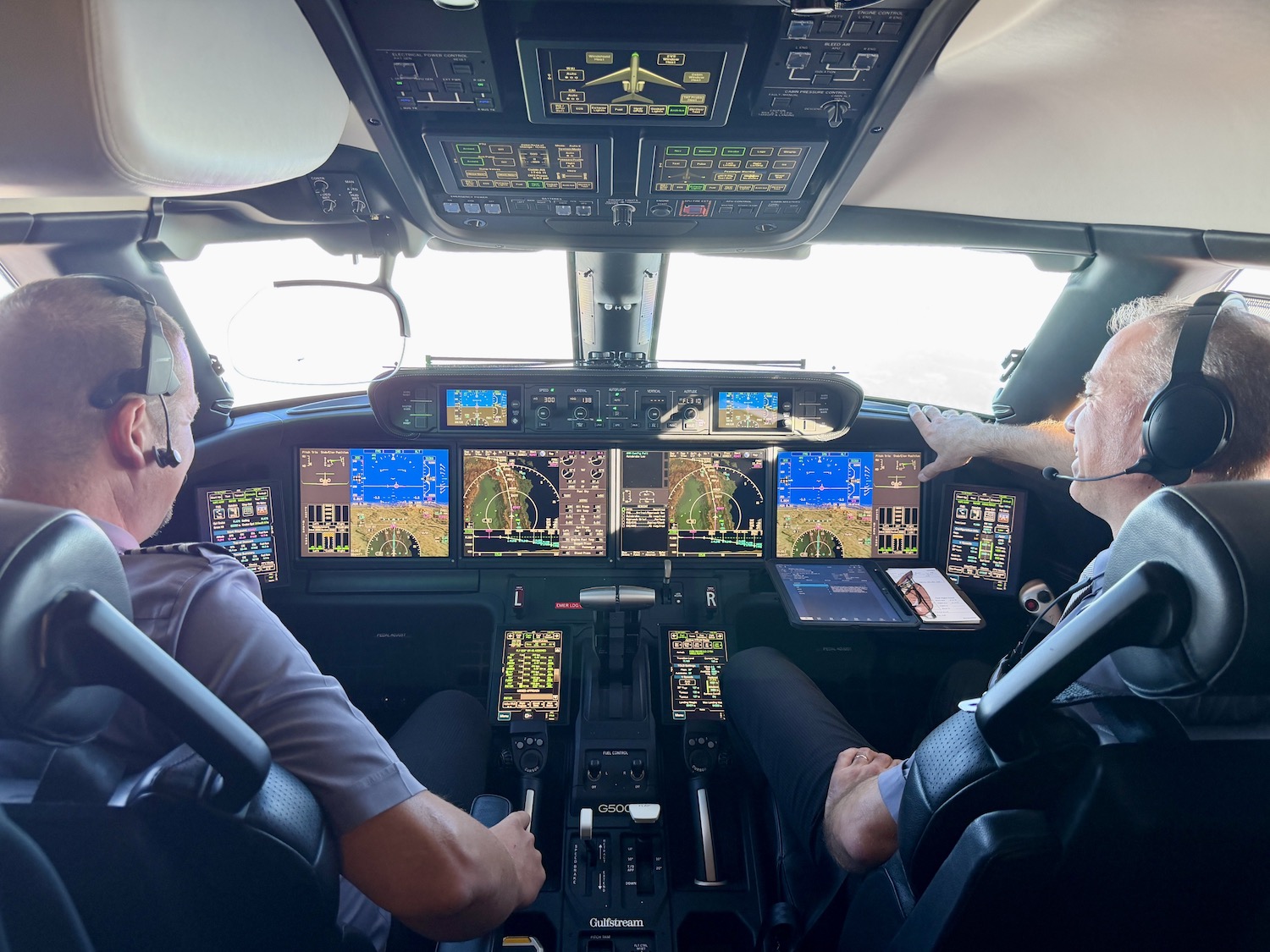 Cockpit view of two Flexjet pilots operating a Gulfstream G500 jet, monitoring instruments and navigation displays.