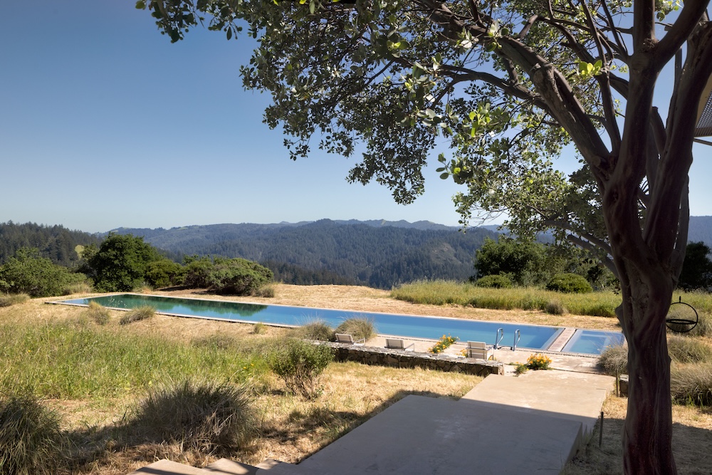 A modern retreat showcasing a serene pool surrounded by lush hills and trees in West Marin's picturesque landscape.