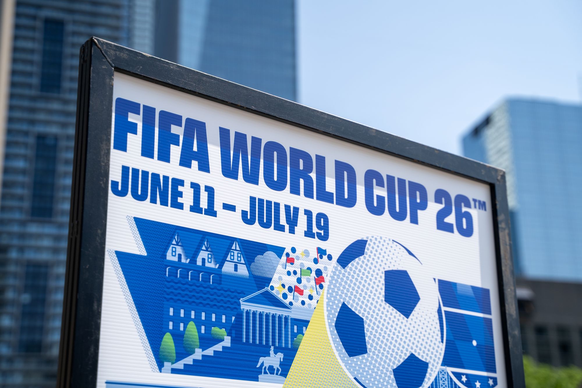 FIFA World Cup 2026 promotional sign displaying dates June 11 to July 19, with soccer ball and vibrant graphics.