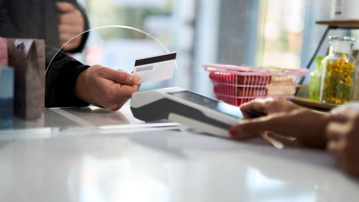 A customer hands a credit card to a cashier while making a payment at a counter.