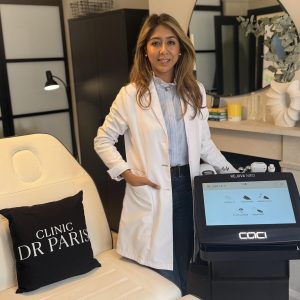 Dr. Paris stands beside the CACI Rejuva Med™ machine in a modern clinic setting, promoting high-tech facial treatments.