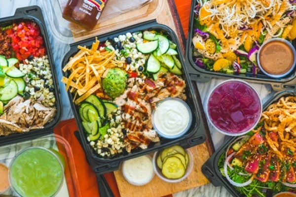 Colorful salad boxes featuring fresh vegetables, grilled chicken, and dressings, perfect for summer gatherings and celebrations.