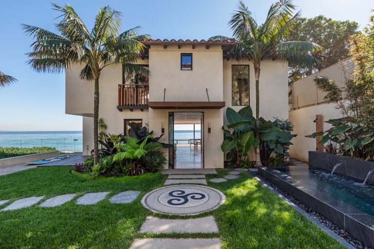 Modern beachfront property in Malibu with lush landscaping and ocean views.