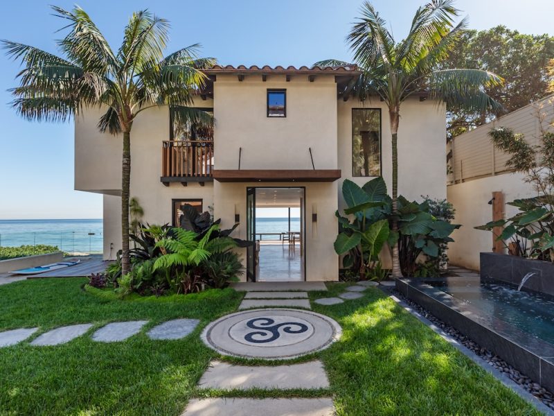 Modern beachfront property in Malibu with lush landscaping and ocean views.
