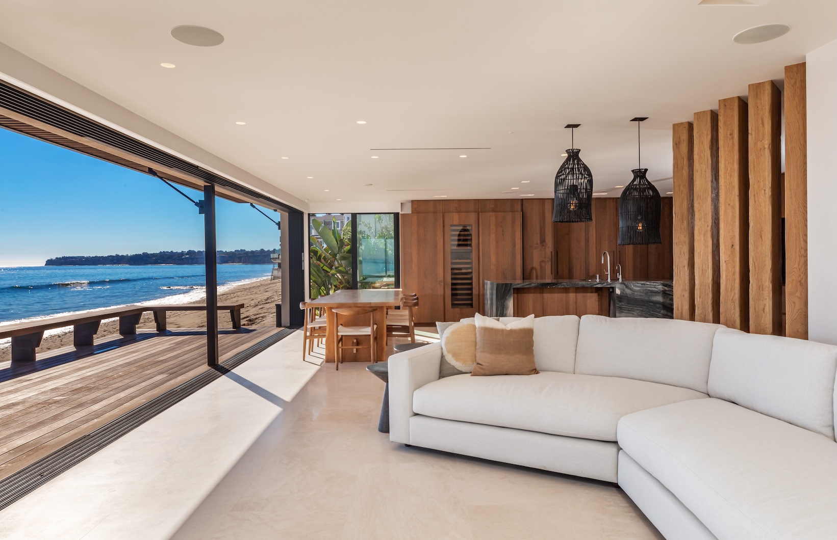 Bright and airy beachfront living space with modern furnishings and ocean views through large sliding glass doors.