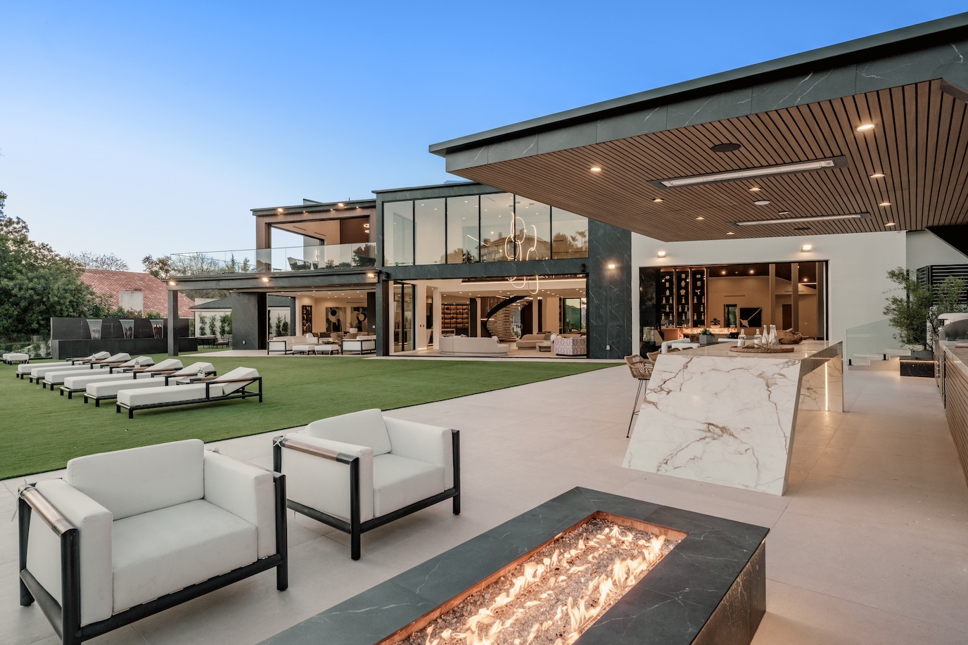 Contemporary outdoor living space featuring a sleek poolside area, modern furniture, and expansive glass walls of a luxury home.