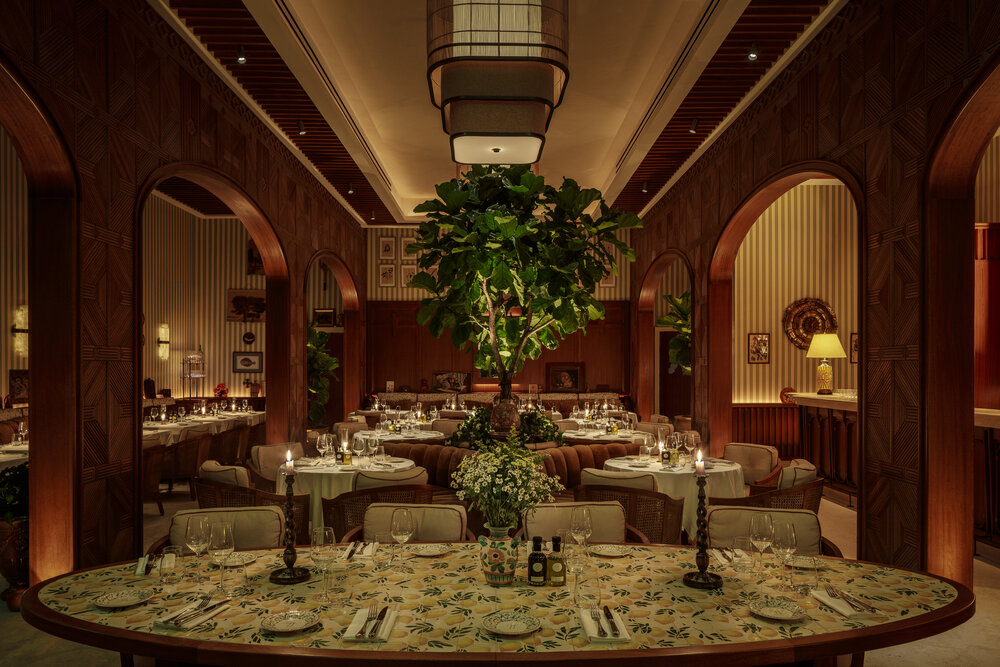Elegant dining area at DRAFT Delano Miami Beach featuring lush greenery, stylish decor, and candlelit tables.