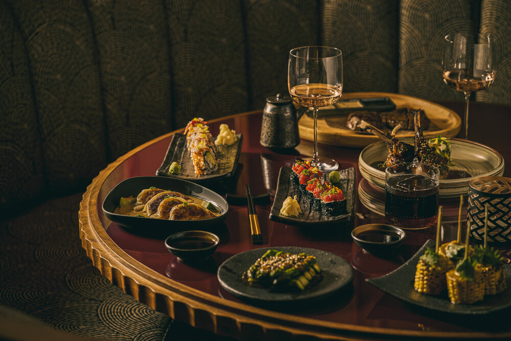 A beautifully arranged table featuring sushi, dumplings, grilled meats, and drinks, showcasing a luxurious dining experience.