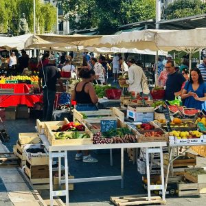 Busy market scene showcasing vibrant fruits and vegetables at Nice's Marché de la Libération under sunny skies.