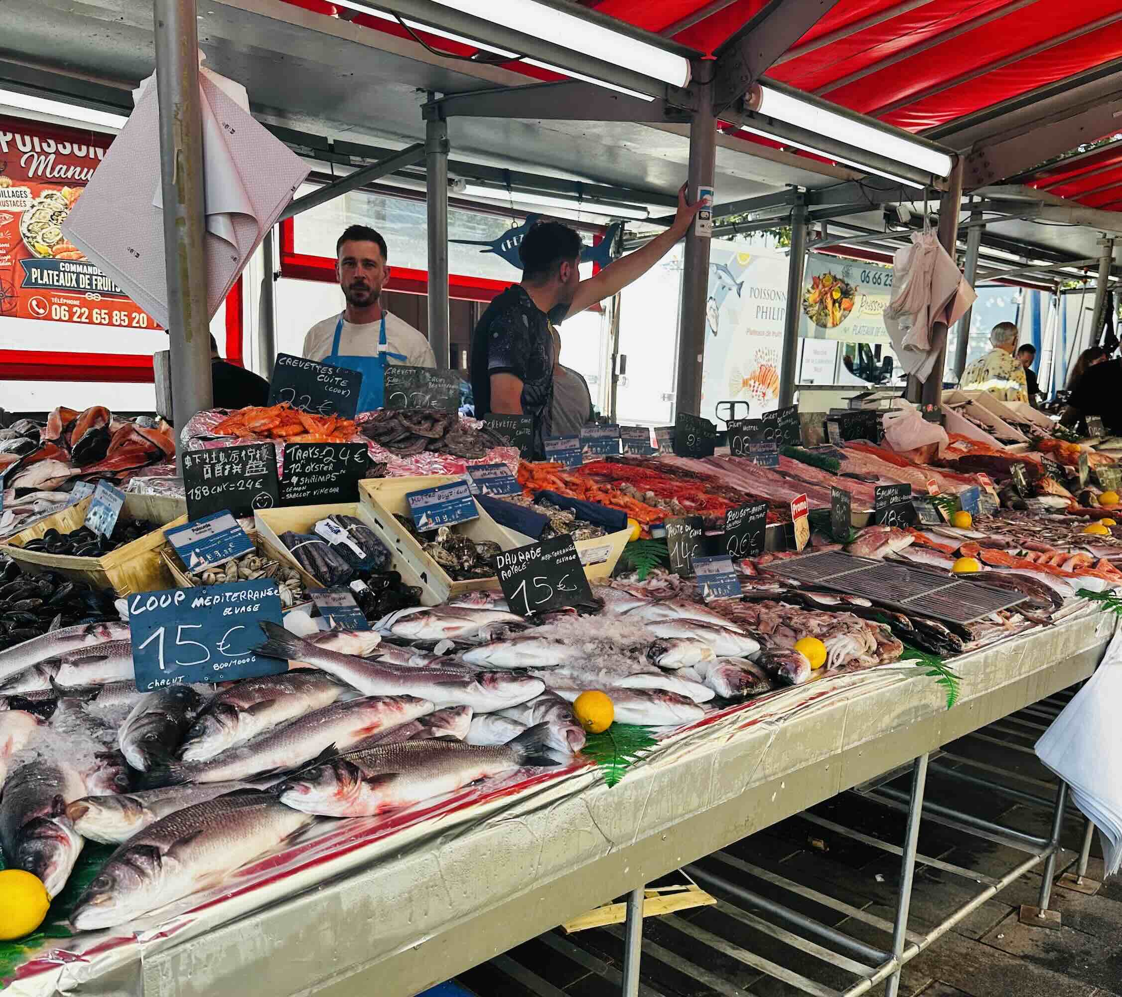 Vibrant seafood market stall at Marché de la Libération, showcasing fresh fish and shellfish under a red awning.
