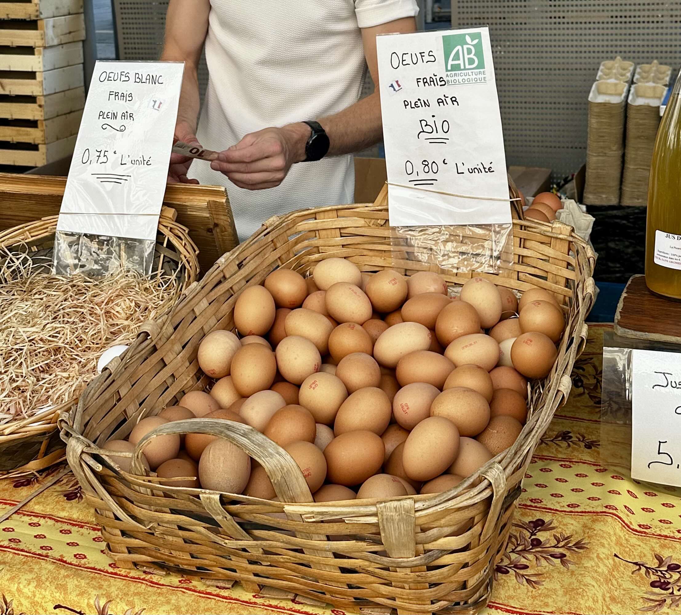A basket of fresh brown eggs at Marché de la Libération, with price signs for both organic and standard options.
