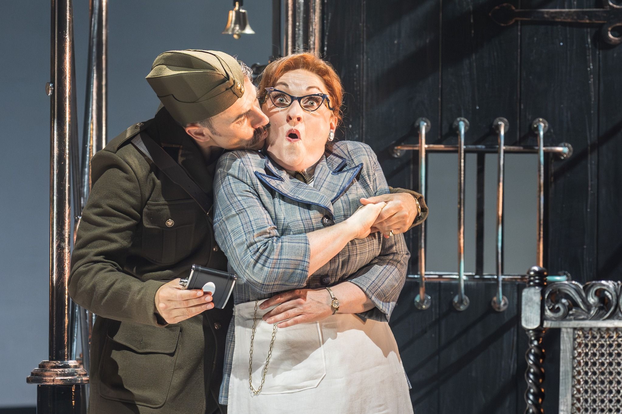 A dramatic scene from Il Barbiere di Siviglia featuring a soldier and a surprised woman in a barber shop setting.