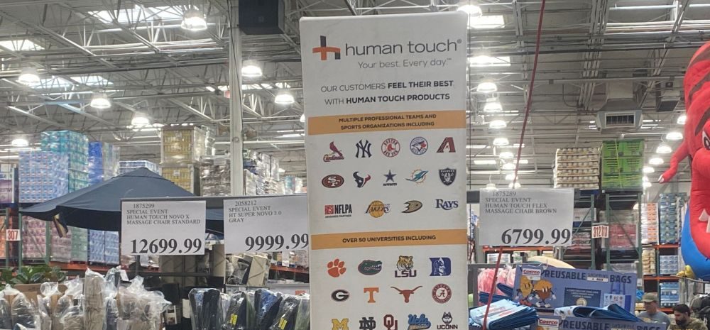 Human Touch massage chair display with pricing and details on brand partnerships at a Costco warehouse.