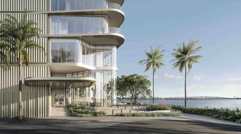 Modern luxury waterfront building entrance with palm trees and a view of the water in Miami.