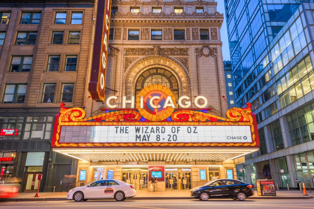 Chicago theater marquee displaying "The Wizard of Oz" from May 8 to 20, surrounded by city buildings and traffic.