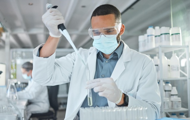 A lab technician using a pipette while analyzing samples, focused on peptide trends in a modern laboratory setting.