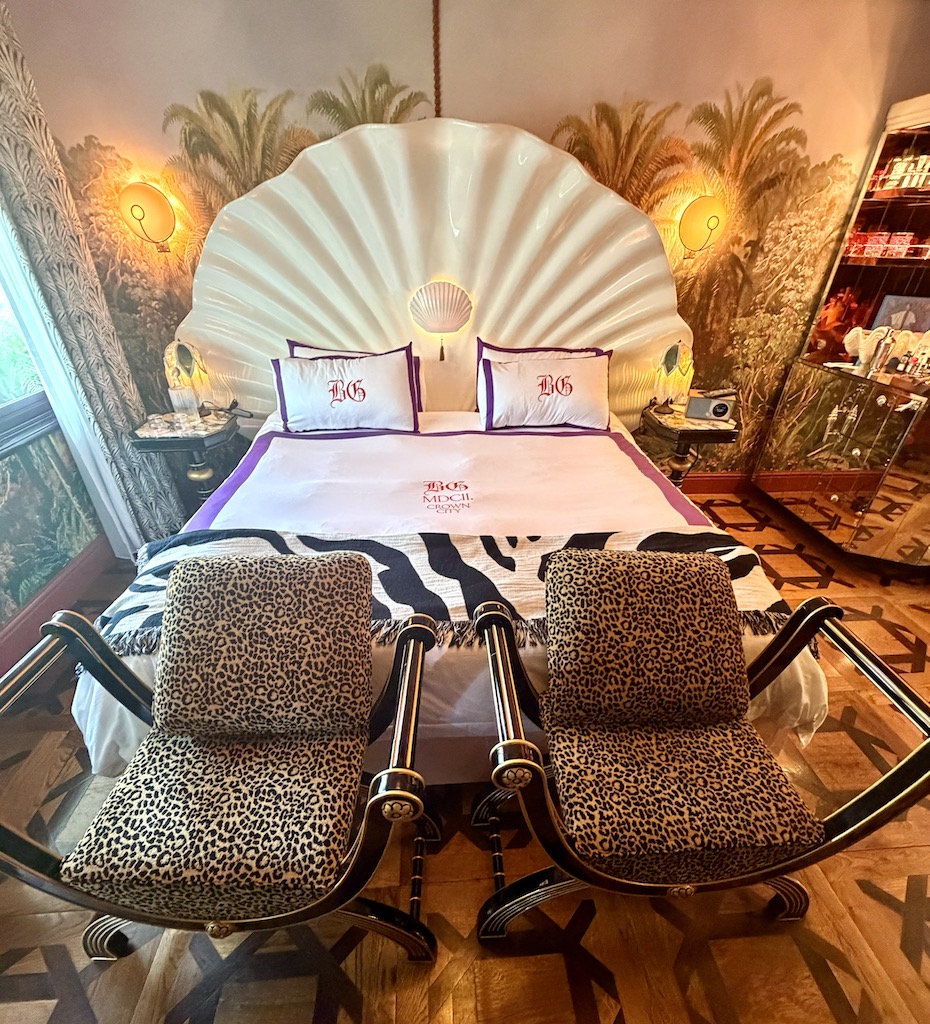 Elegant bedroom at The Baby Grand, featuring a shell-shaped headboard, zebra-patterned throw, and stylish leopard-print chairs.