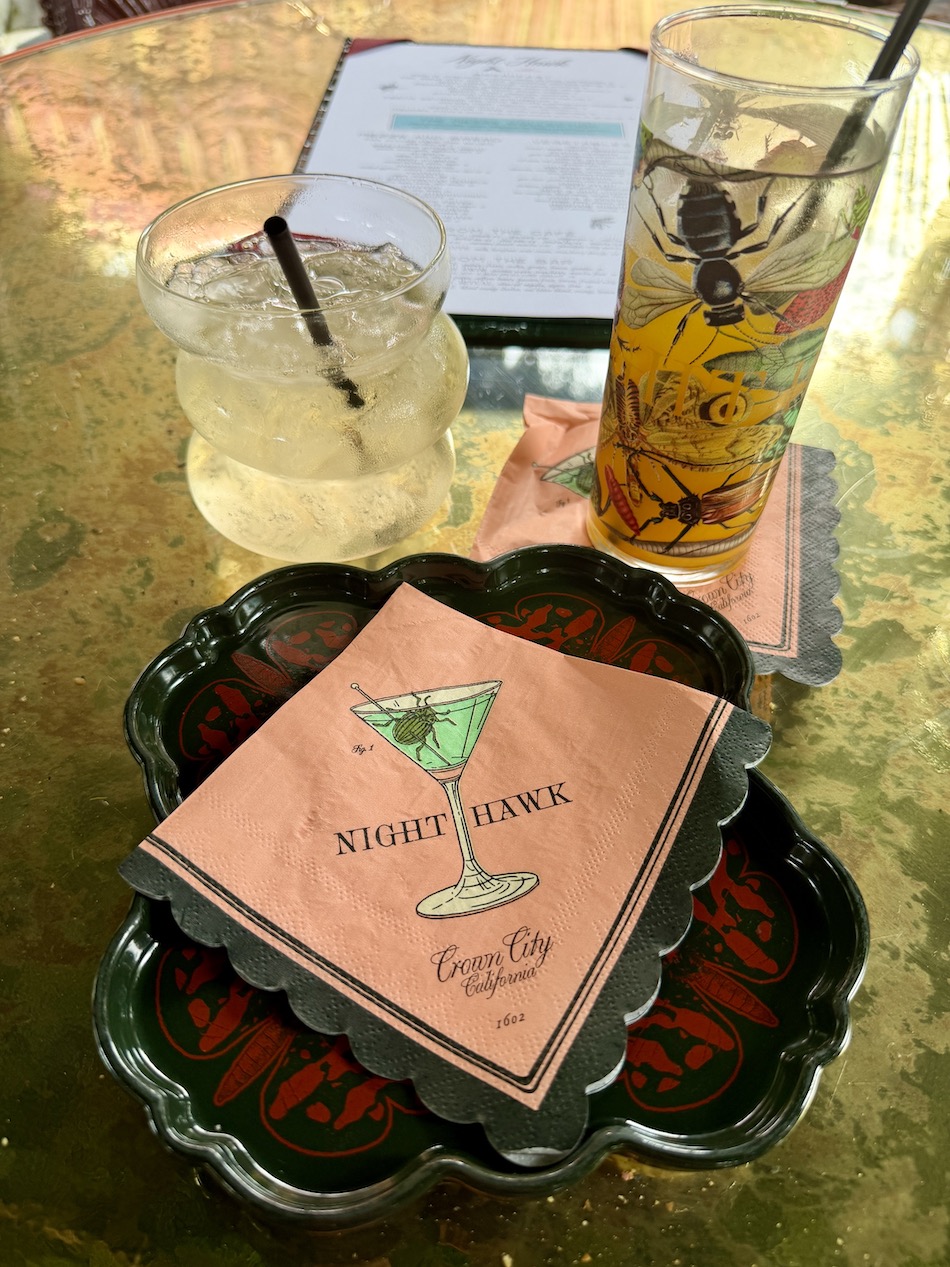 Drinks and a cocktail napkin with "Night Hawk" on a decorative tray at The Baby Grand in Coronado.