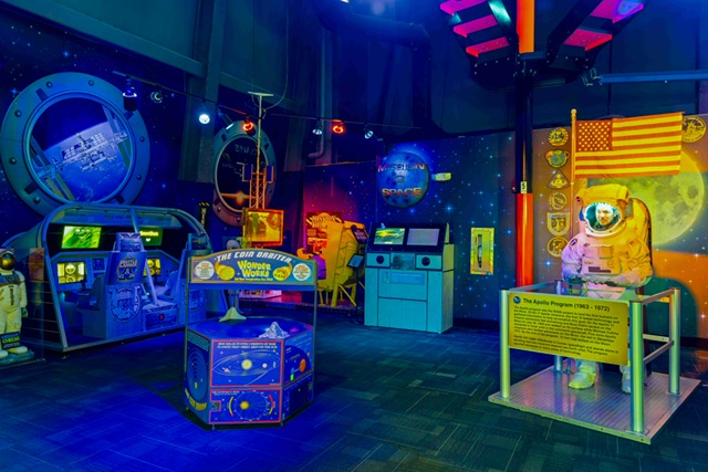 Exploration-themed exhibit featuring an astronaut suit, interactive displays, and space visuals at WonderWorks Myrtle Beach.