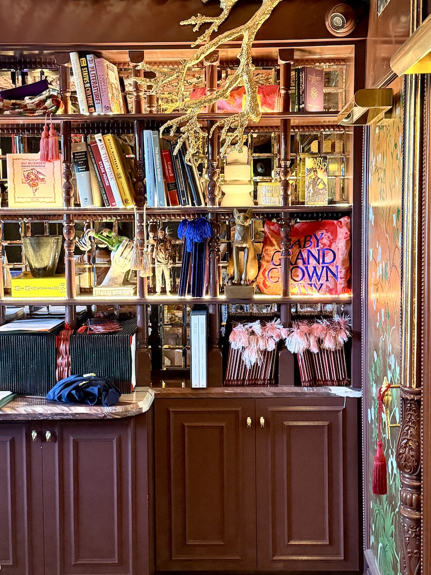 A stylish bookcase filled with books, decorative items, and vibrant accents at The Baby Grand in Coronado.