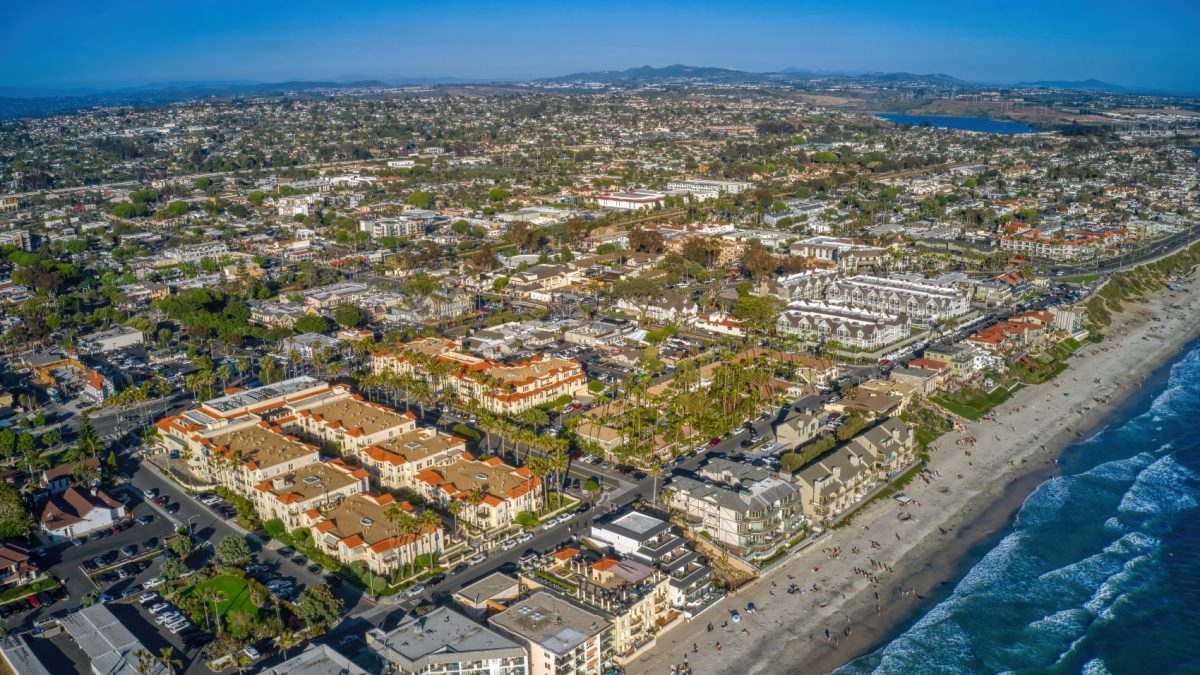 Aerial view of Carlsbad featuring beachfront property, residential areas, and vibrant urban landscape under a clear blue sky.