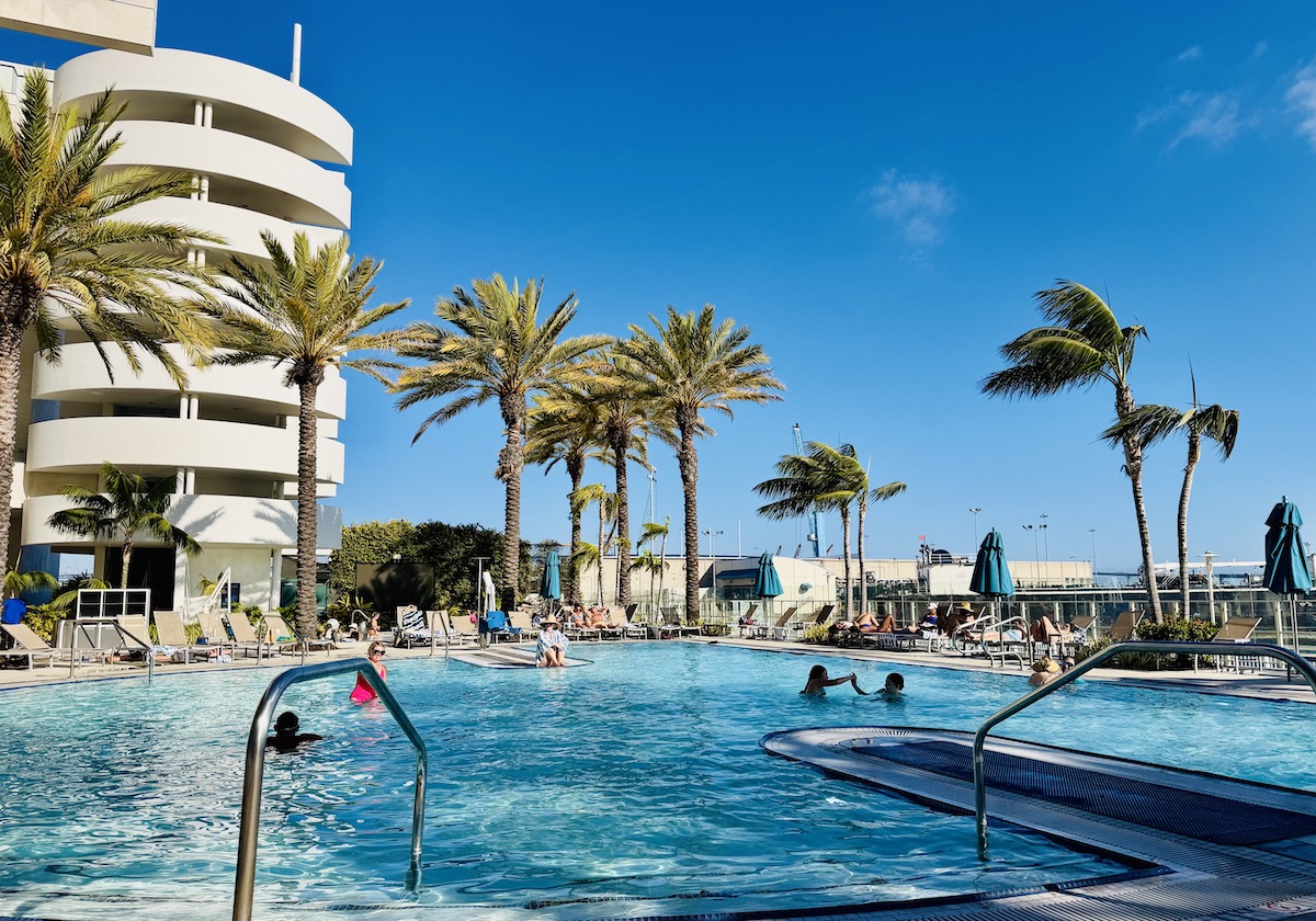 Sunny pool area at the luxury Hilton San Diego Bayfront, surrounded by palm trees and guests enjoying the water.