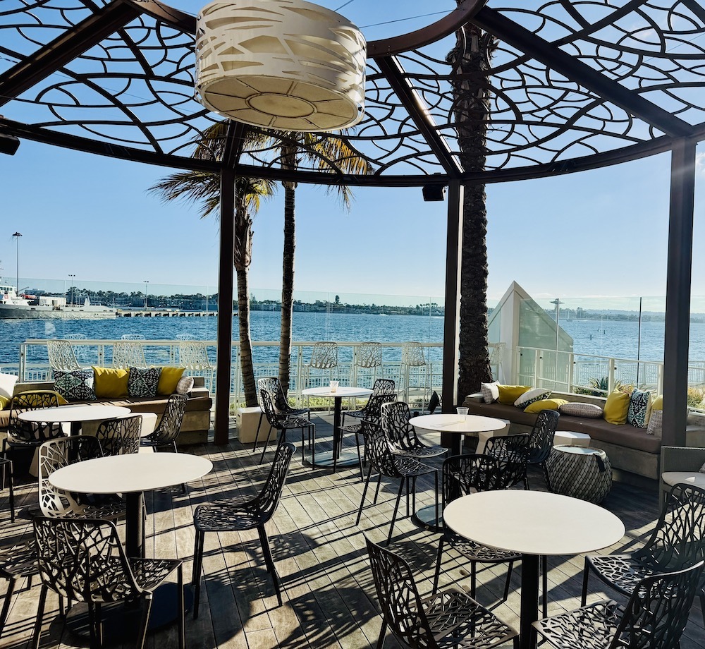 Open-air seating area at The Pool Bar, featuring modern chairs, tables, and a scenic view of San Diego Bay.